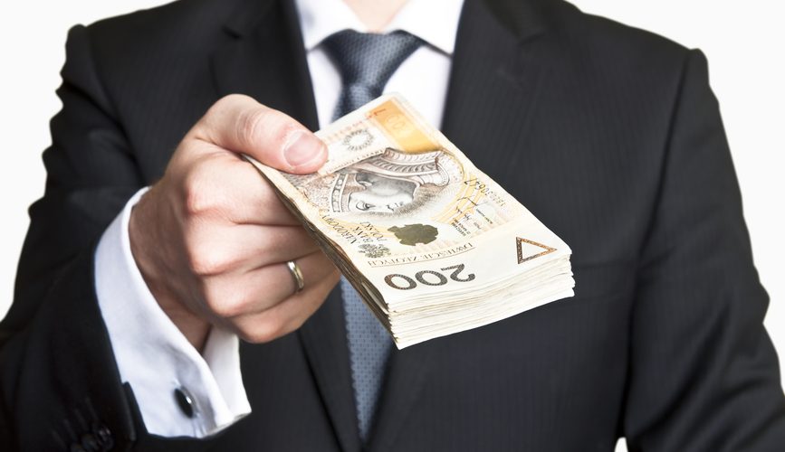 Businessman wearing suit and tie handing a lot of Polish money