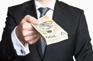 Businessman wearing suit and tie handing a lot of Polish money